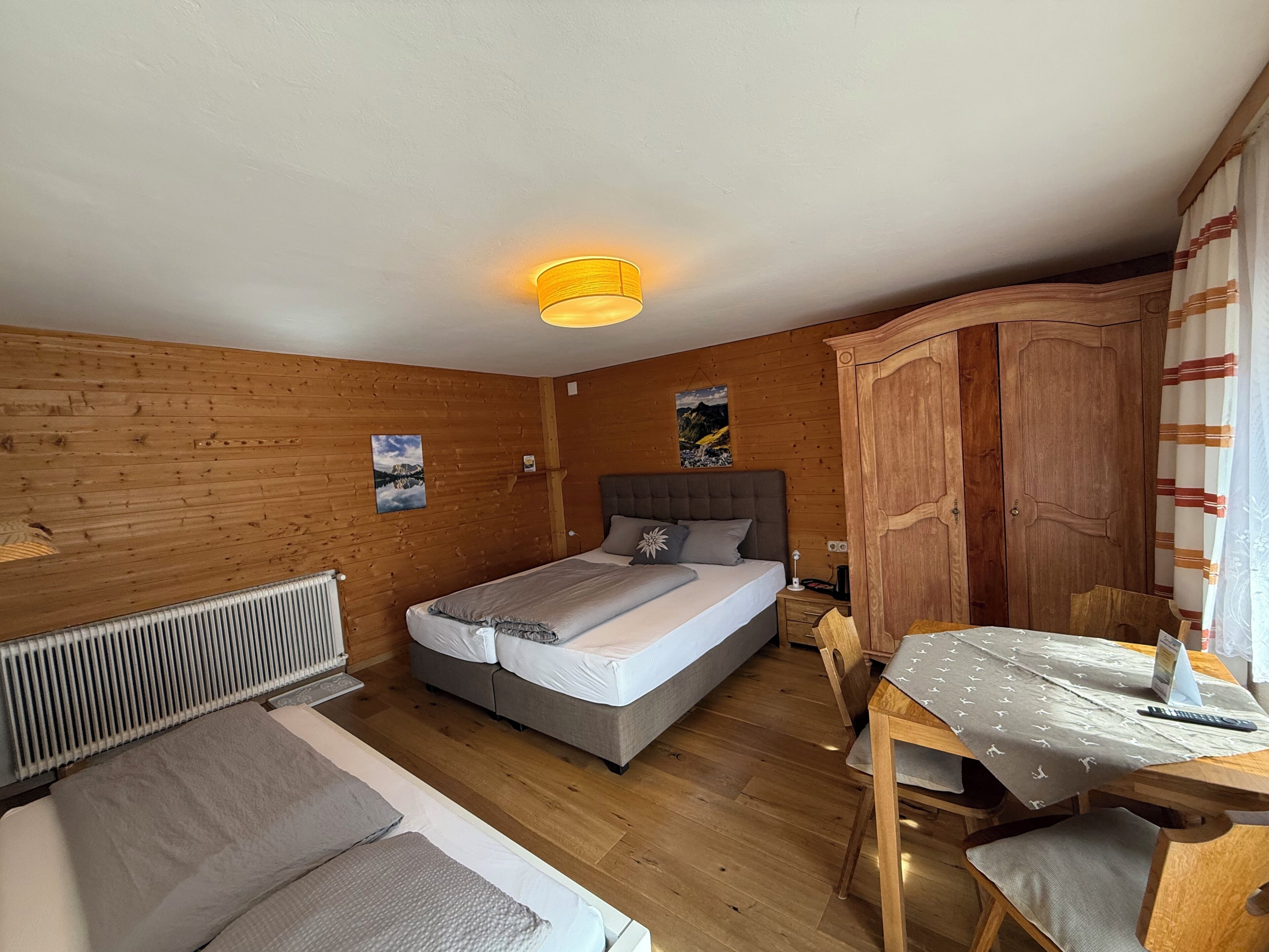 Una habitación con paneles de madera, una cama, una mesa y un armario.