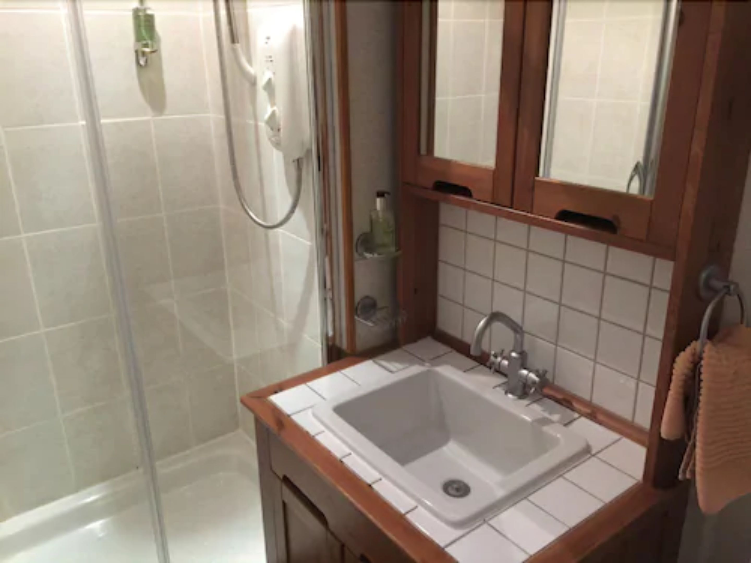 Un baño con ducha, lavamanos y espejo.