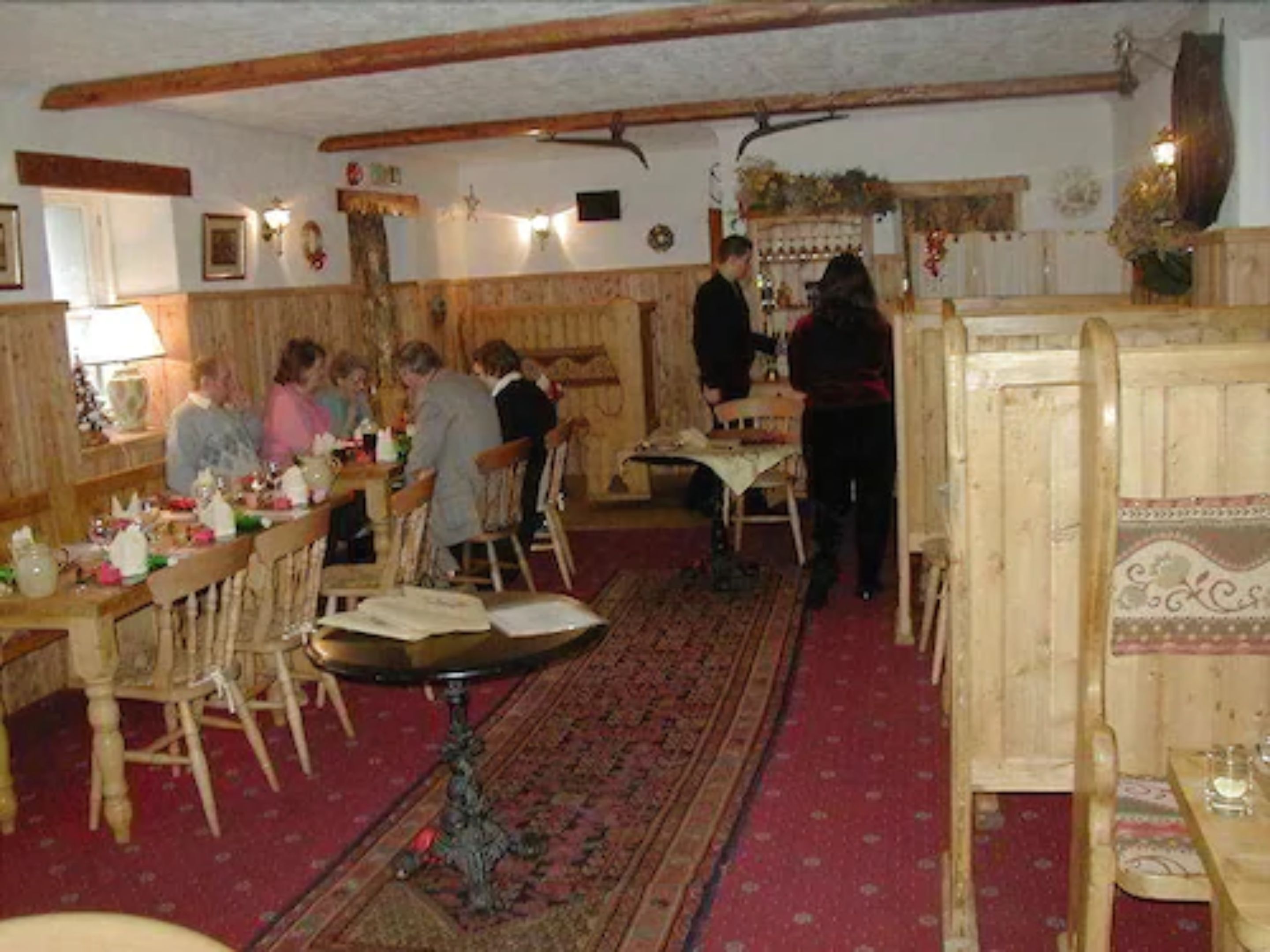A traditional inn with wooden furniture, a central table, and a patterned carpet.