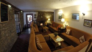 A cozy living room with a stone wall, a fireplace, and a wooden sofa. - The Old Inn (Gairloch)
