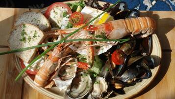 A seafood platter with shrimp, mussels, and oysters on a plate, accompanied by slices of bread and garnishes.