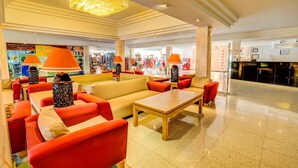 A spacious lobby with a beige sofa, red chairs, and a wooden coffee table.