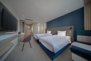 Una habitación de hotel moderna con dos camas, un escritorio, un televisor y una silla.
