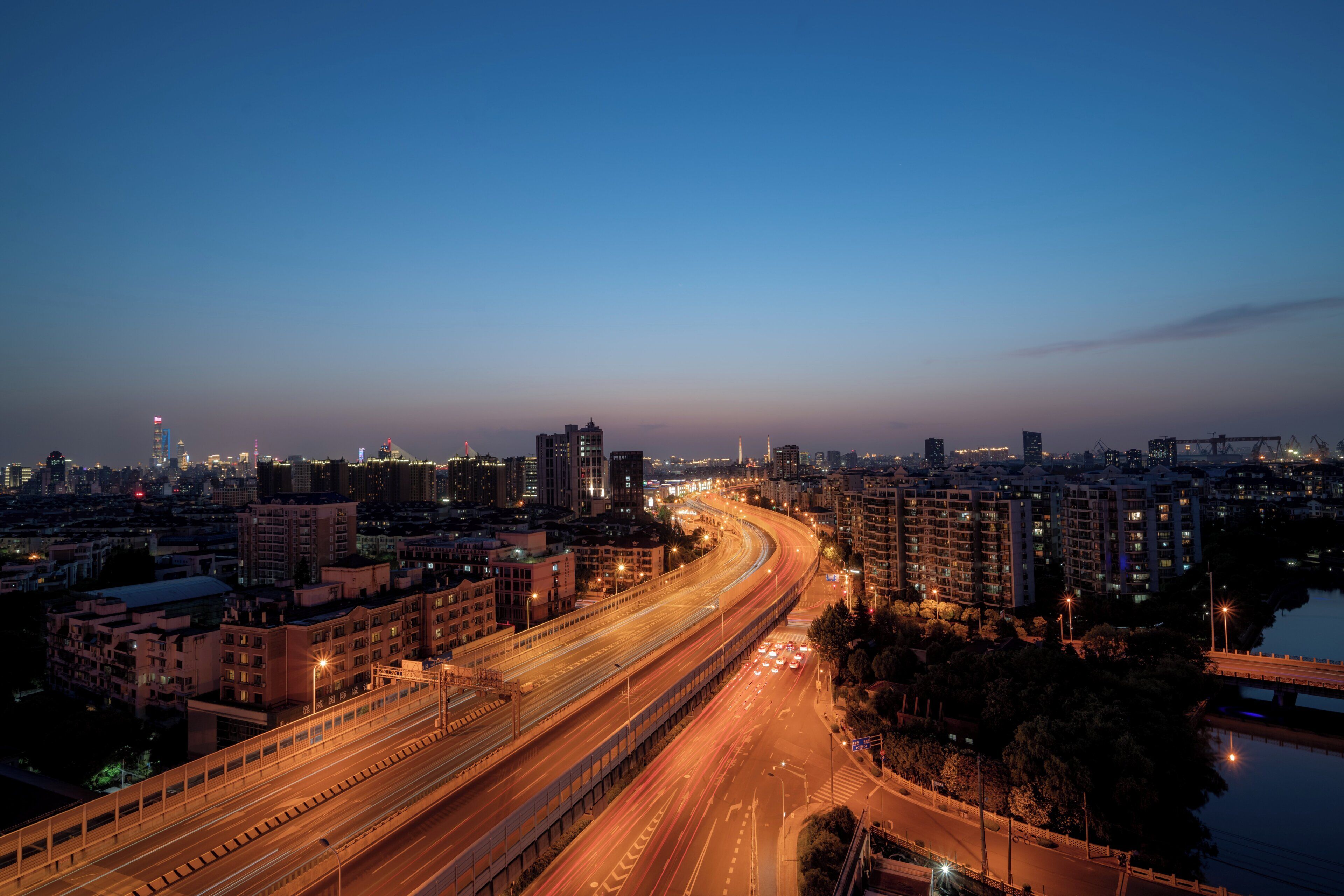 A cityscape at dusk with a curved highway and multiple buildings.