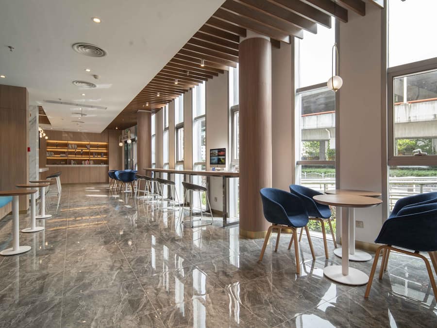 A modern hotel lobby with a long reception desk, blue chairs, and a blue sofa.