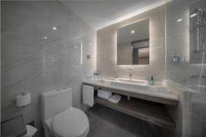 Un baño moderno con inodoro, lavamanos y ducha.