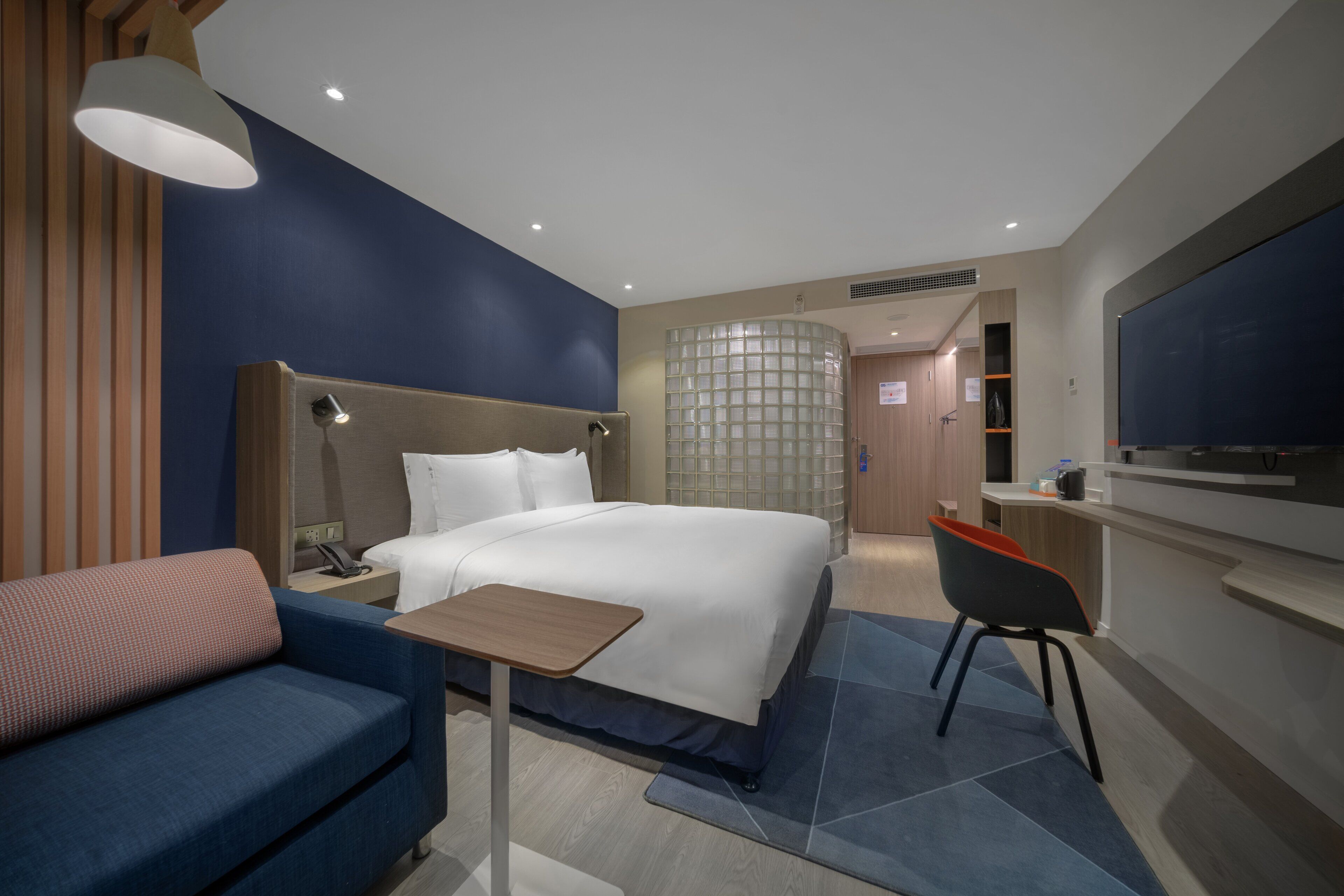 Une chambre d’hôtel moderne équipée d’un grand lit, d’un bureau, d’une chaise et d’un téléviseur.