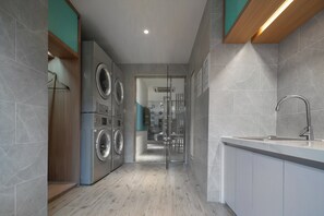 Una cucina moderna con lavatrice integrata, lavello e porta vetrata che dà su un bagno.