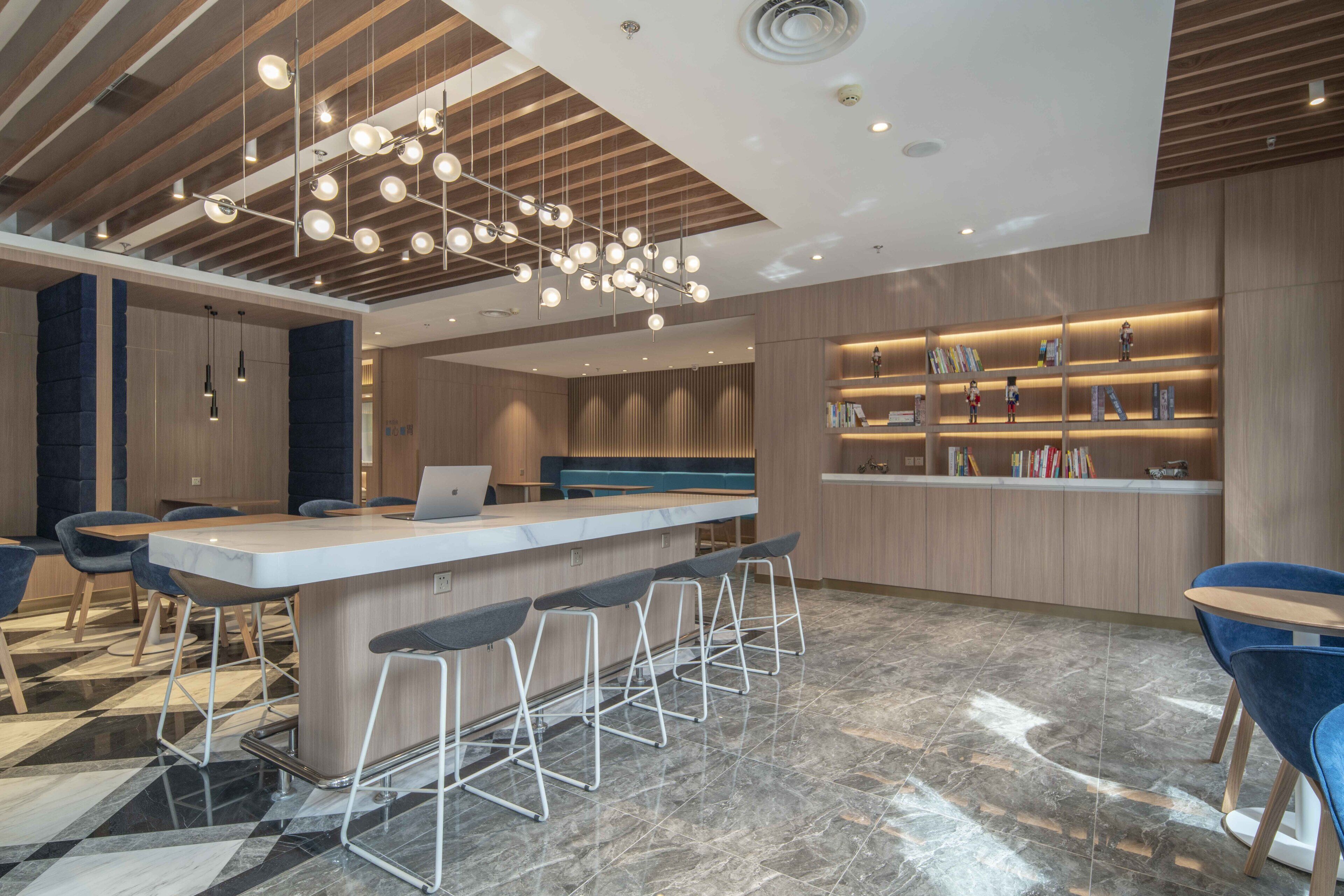 A modern bar area with a central island, bar stools, and a ceiling with hanging lights.