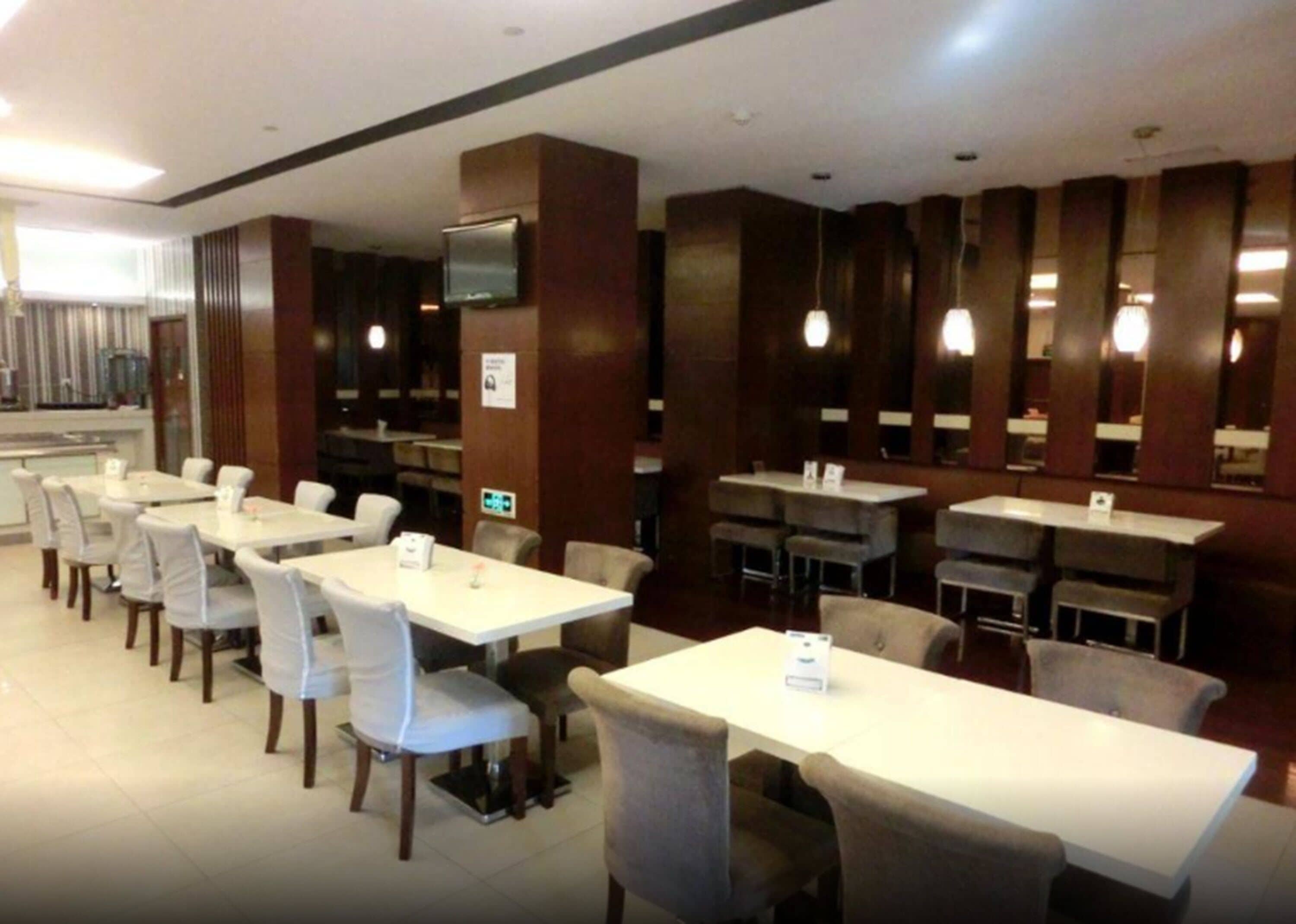 Ein Restaurant mit mehreren Tischen und Stühlen, einem an einem Pfeiler befestigten Fernseher und modernem Interieur.