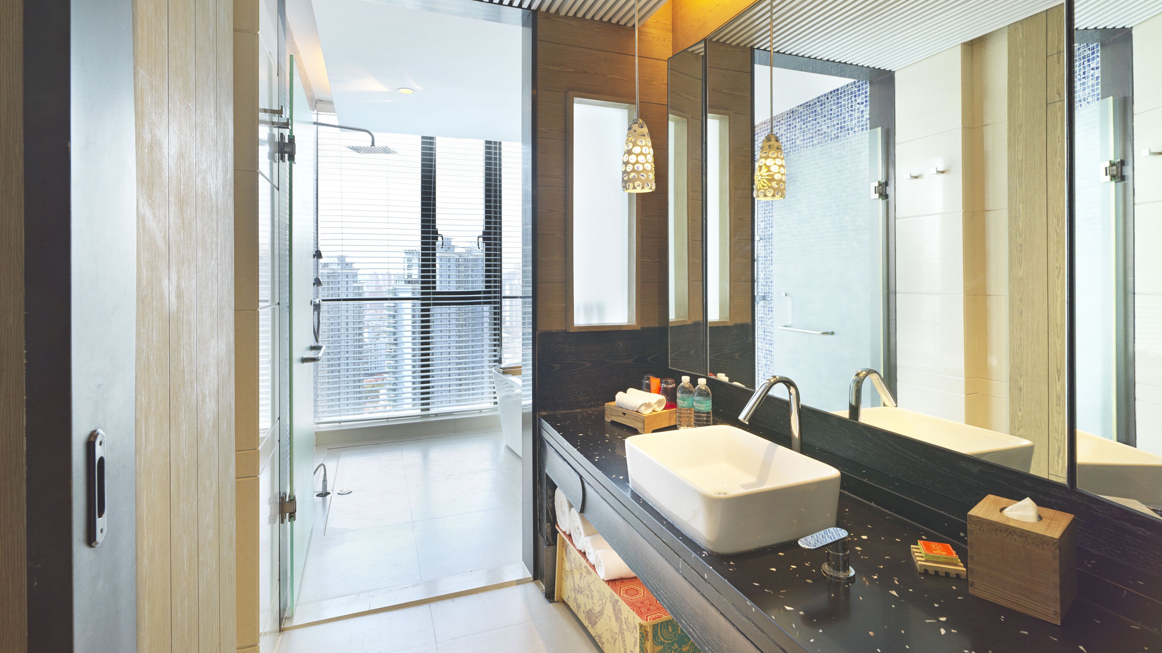 A modern bathroom with a large mirror, a white sink, and a shower area.
