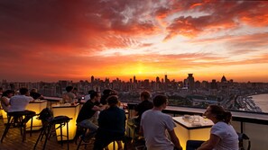 Un bar en la azotea con vistas al horizonte de la ciudad al atardecer.