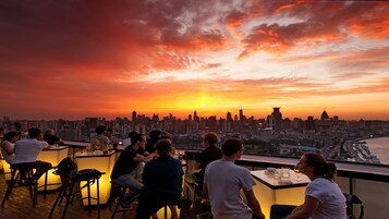 A rooftop bar with a city skyline view at sunset.