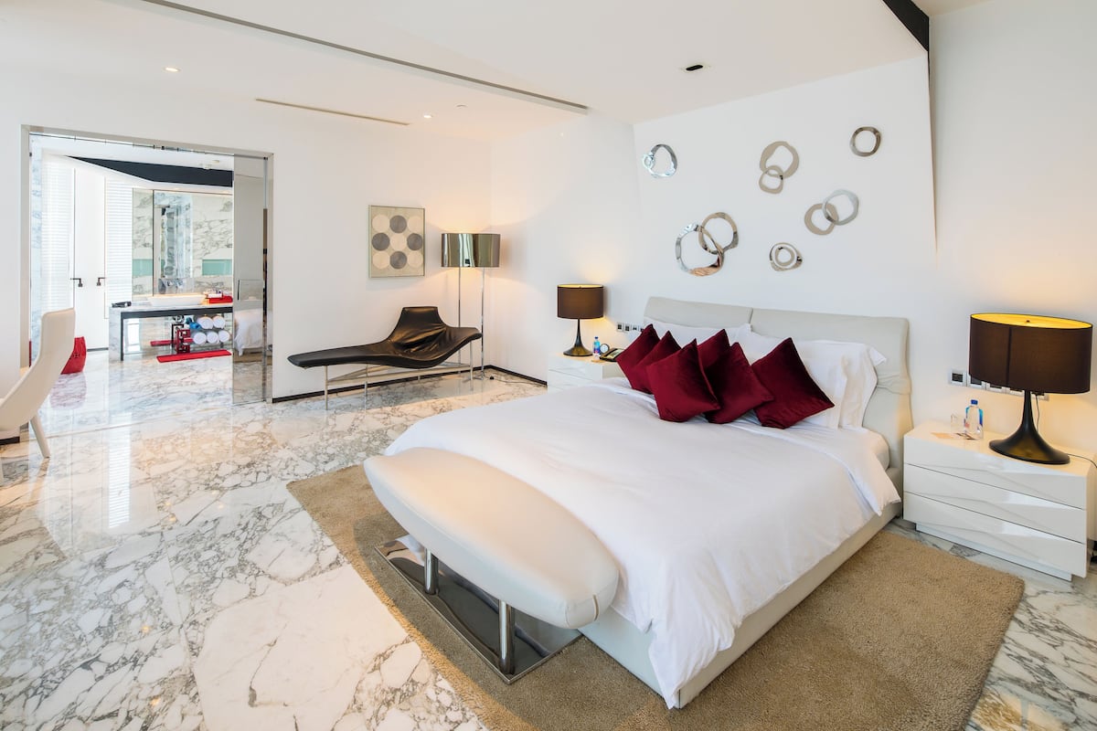 Une chambre moderne avec un grand lit, des tables de chevet, une chaise et un miroir.
