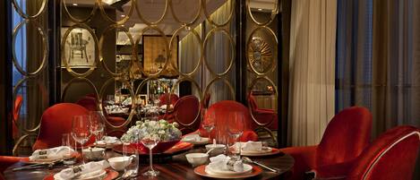 Comedor con una mesa redonda dispuesta para seis personas, rodeada de sillas tapizadas en rojo.