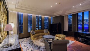 Ein geräumiges Wohnzimmer mit großem Fenster, einer Couch, einem Fernseher und einem Schreibtisch mit Computer.