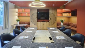 A conference room with a long table, black chairs, and a wooden cabinet with a TV. - Mercure Chartres Centre Cathédrale (Chartres)