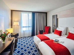 A hotel room with a bed, a desk, a chair, a lamp, and a window with curtains. - Mercure Chartres Centre Cathédrale (Chartres)
