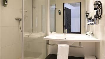 A modern bathroom with a glass-enclosed shower, a white sink, and a mirror.