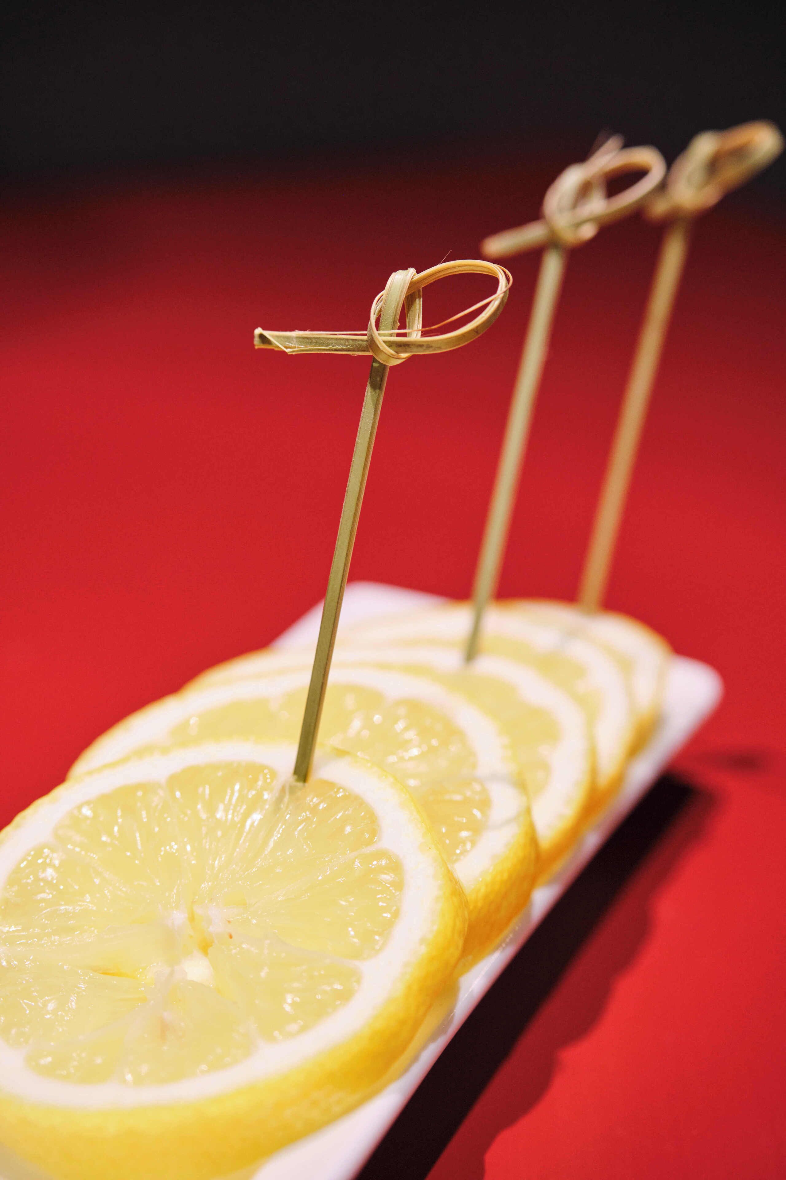 Un piatto bianco con fette di limone e stuzzicadenti.