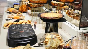 Un bufé con diversas opciones de comida, incluyendo pan, pasteles y una máquina para gofres.