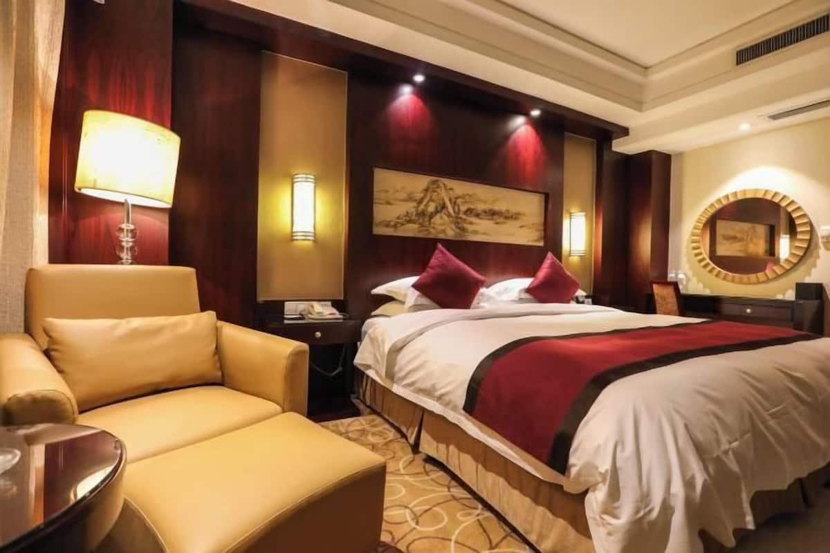 Ein Hotelzimmer mit Bett, Sofa, Nachttisch und Lampe.