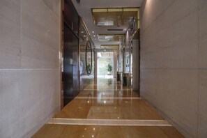 A corridor with reflective flooring and walls, leading to a bright area with natural light. - Fubang International Hotel (Hangzhou)