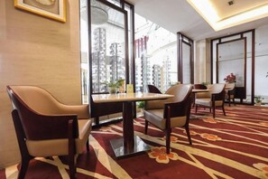 A hotel room with a large window, a carpeted floor, and a dining area with chairs and a table. - Fubang International Hotel (Hangzhou)