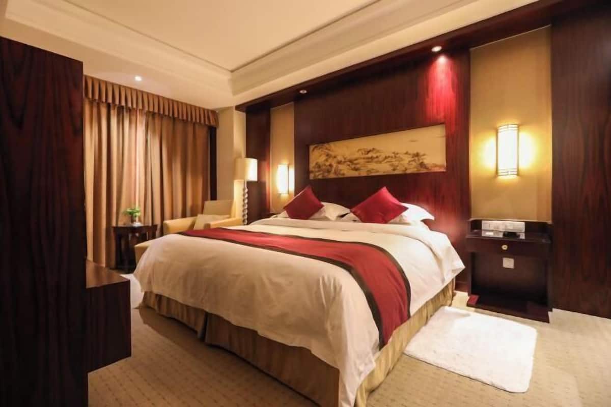 Ein Hotelzimmer mit einem großen Bett, einem Nachttisch, einer Lampe und einem Gemälde an der Wand.