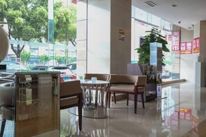 A hotel lobby with a glass partition, seating area, and a plant. - Fubang International Hotel (Hangzhou)