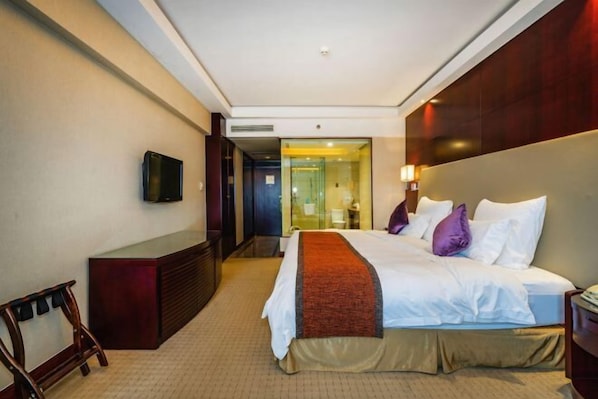A hotel room with a bed, a TV mounted on the wall, a desk, and a mirror. - Fubang International Hotel (Hangzhou)