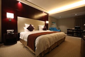 A hotel room with a large bed, a bedside table, a desk, and a chair. - Fubang International Hotel (Hangzhou)