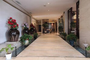 A hotel corridor with potted plants and a marble floor. - Fubang International Hotel (Hangzhou)