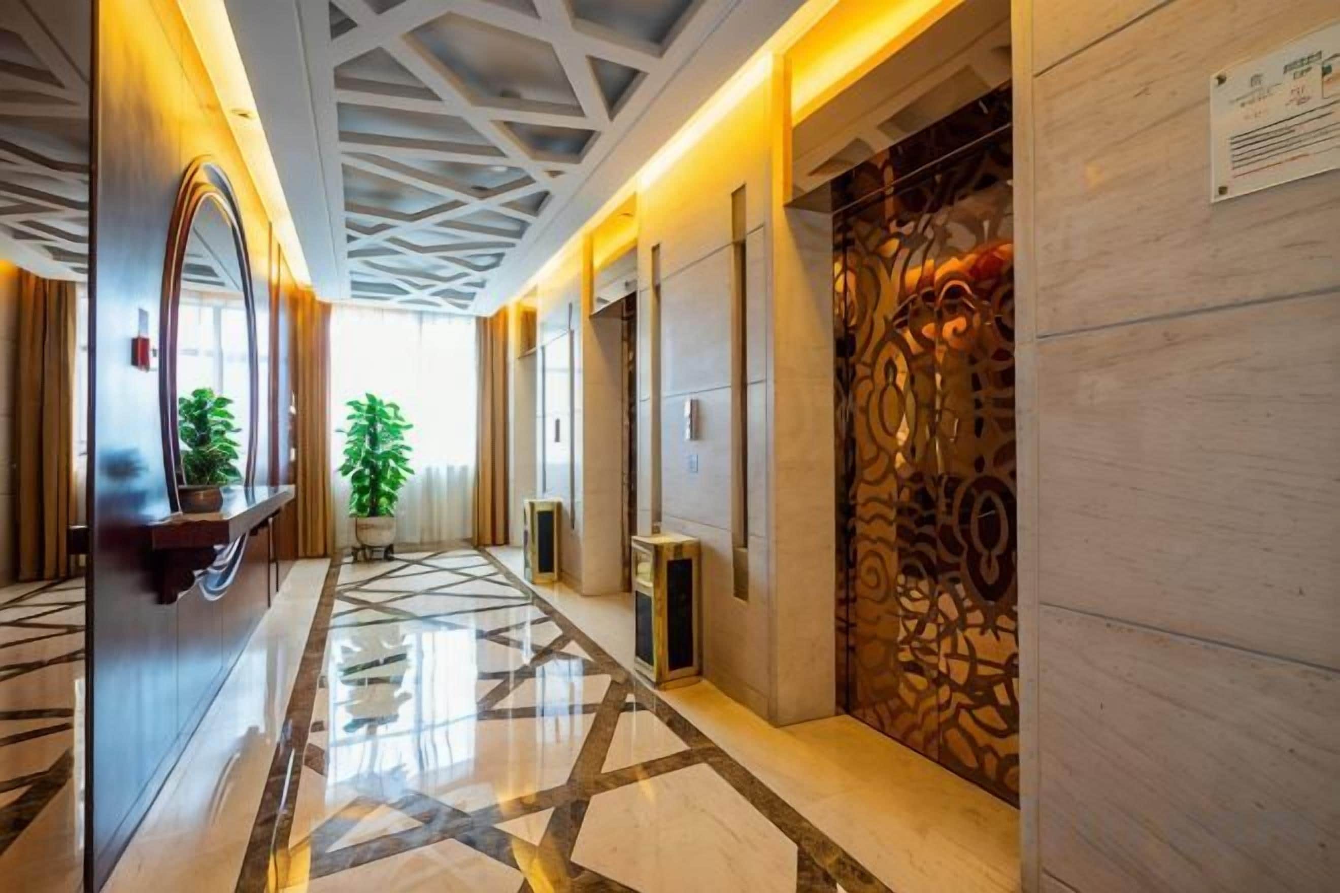 A hotel corridor with a polished floor, a reception desk, and a decorative wall.
