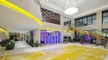 A spacious lobby with a central staircase, a reception area, and a large open area with a polished floor.
