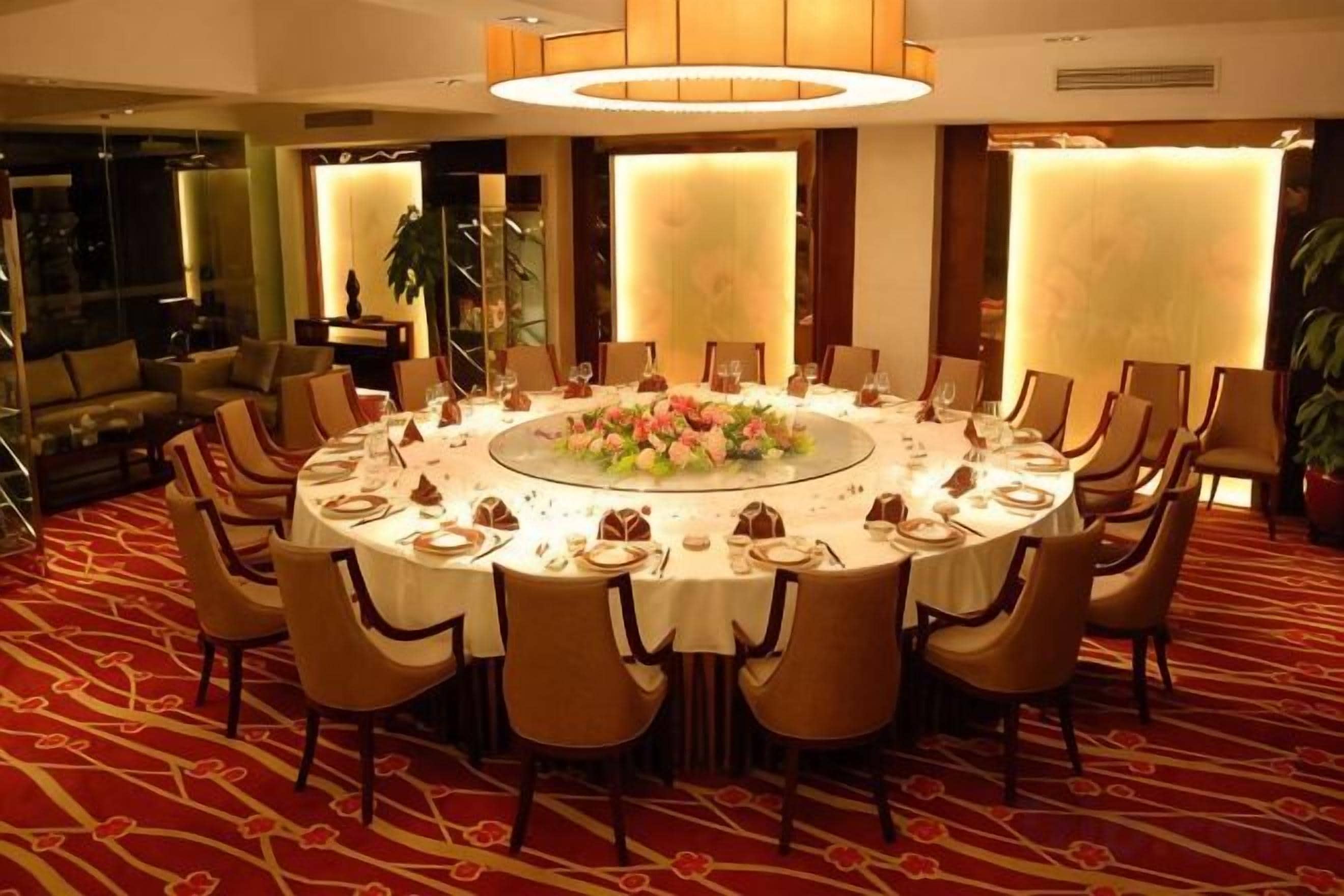 A round dining table with chairs, a floral centerpiece, and a carpeted floor.