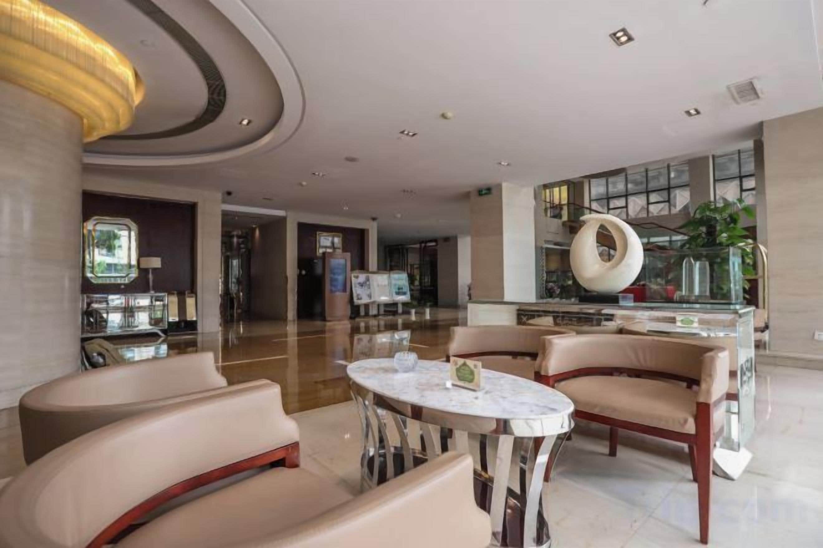 A modern lobby with a marble reception desk, leather seating, and a large glass window.