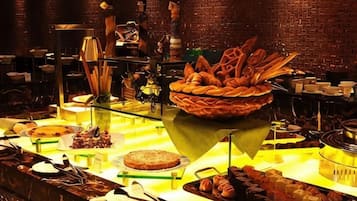 A buffet with various food items and a brick wall in the background.