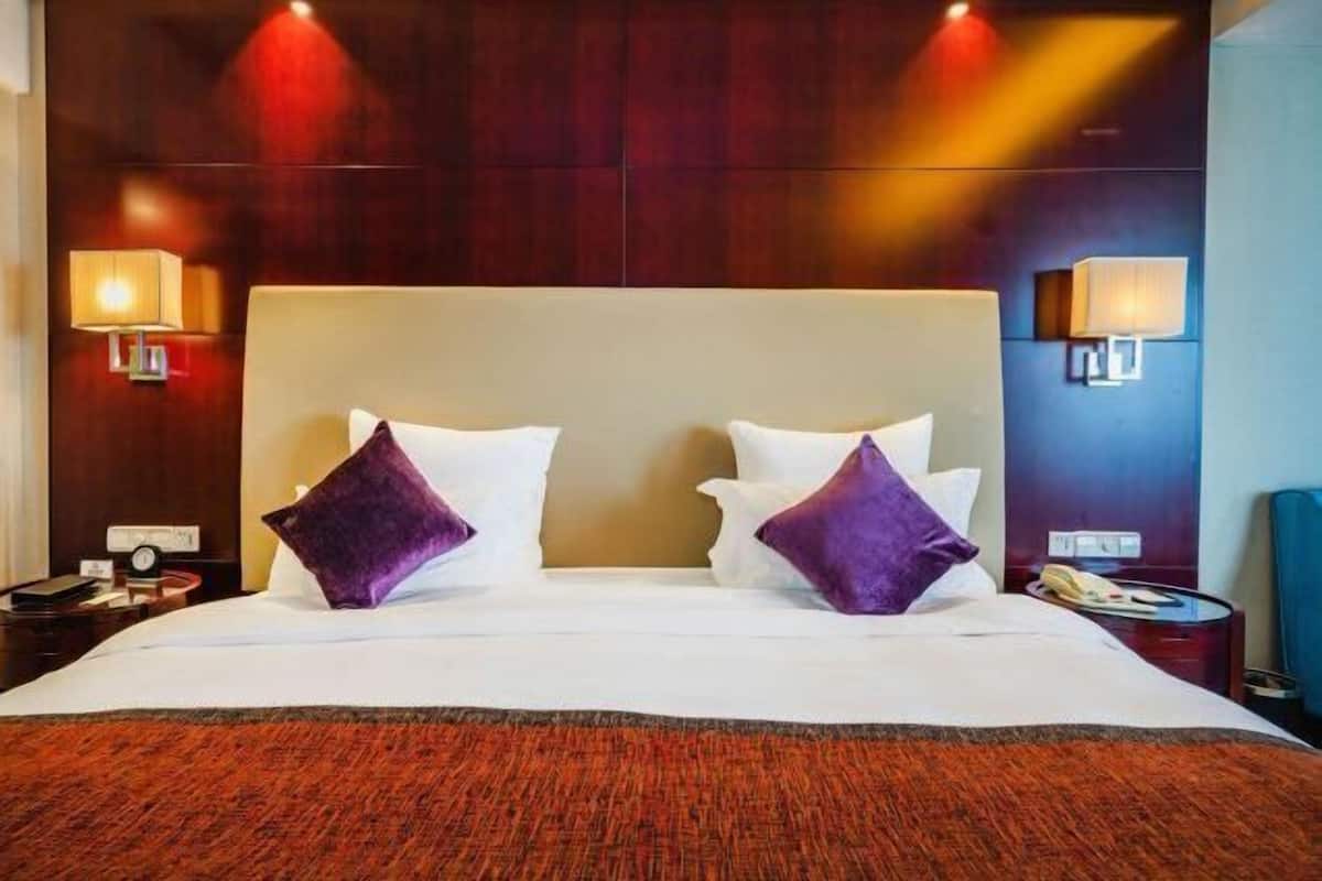 Ein Hotelzimmer mit einem großen Bett, zwei Nachttischlampen, einem Holzkopfschild und einem roten Teppich.