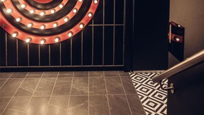A modern interior with a large illuminated sign, dark tiled flooring, and a patterned rug. - Radisson RED Oslo City Centre, A Verified Net Zero Hotel (Oslo)