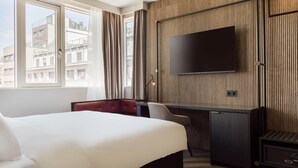 A hotel room with a large bed, a desk with a chair, a TV mounted on the wall, and a view of the city through the window. - Radisson RED Oslo City Centre, A Verified Net Zero Hotel (Oslo)