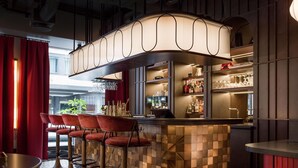 A bar area with a curved counter, red bar stools, and a patterned floor. - Radisson RED Oslo City Centre, A Verified Net Zero Hotel (Oslo)