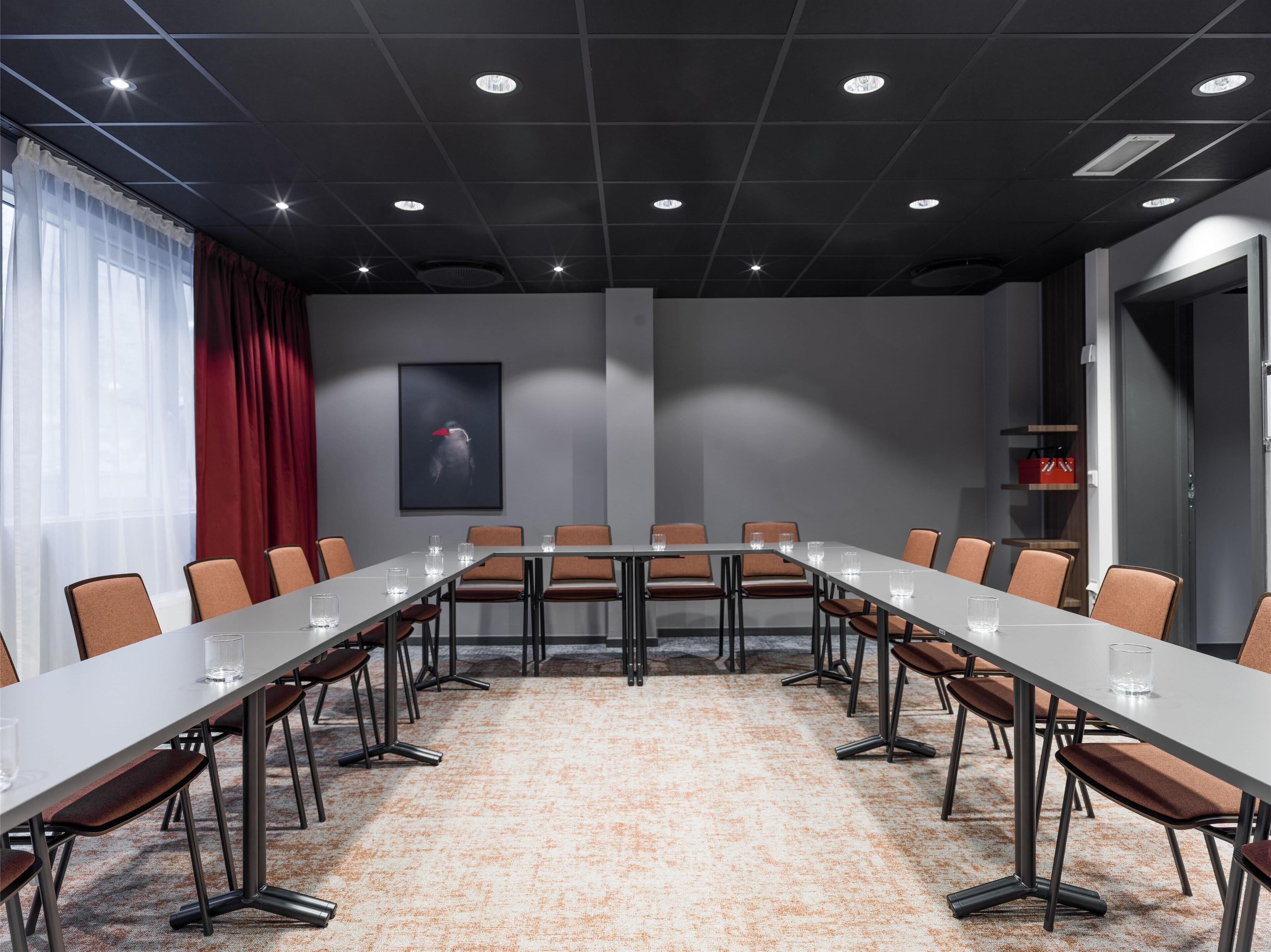 Un salón de conferencias con una larga mesa, sillas y suelo alfombrado.