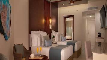 A modern hotel room with two beds, a dining area, and a TV.