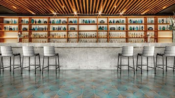 Zona de bar con piso estampado, repisas de madera con botellas y sillas blancas y negras.