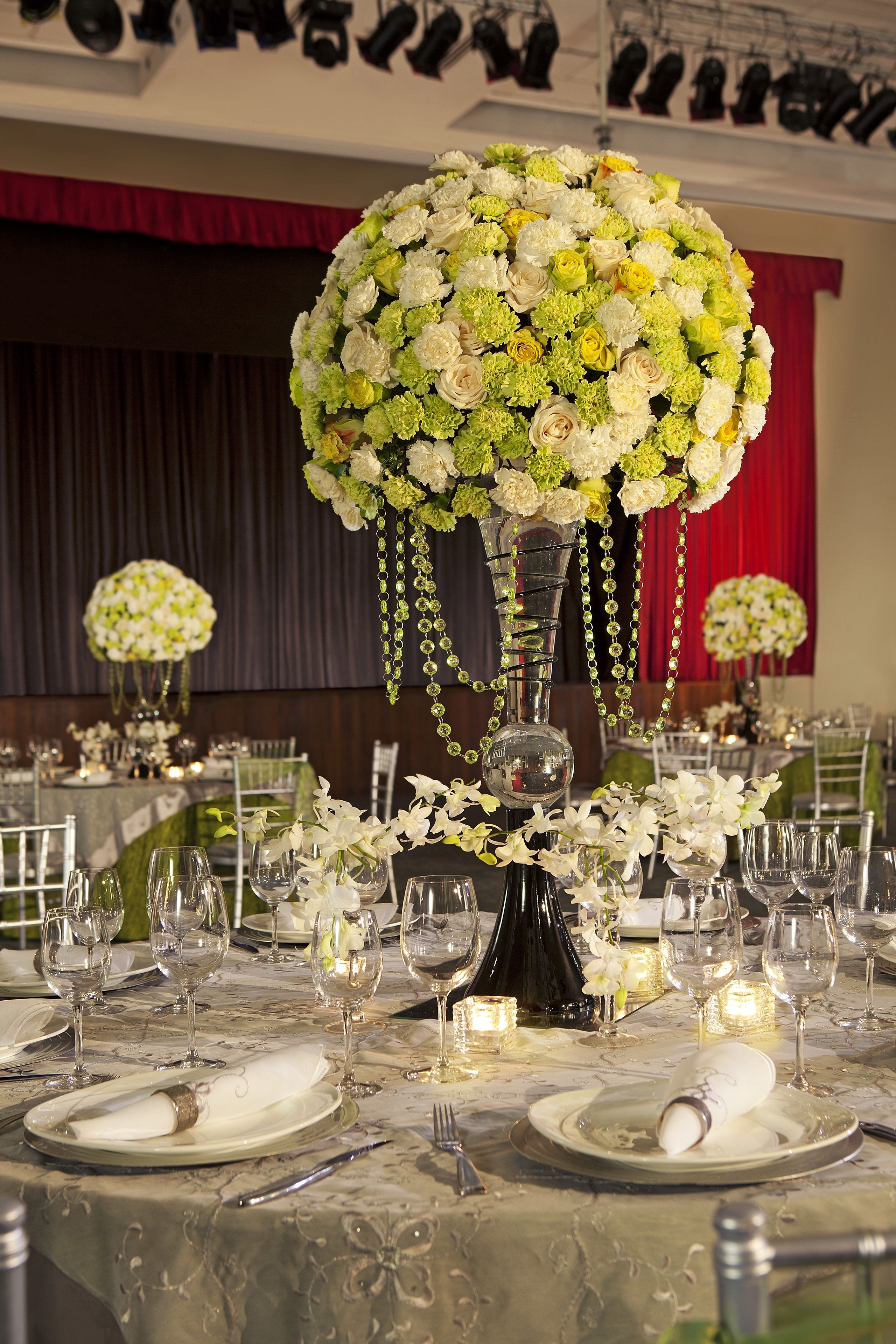 Une table dressée pour un événement formel, agrémentée de compositions florales, de verres transparents et de serviettes pliées avec soin.
