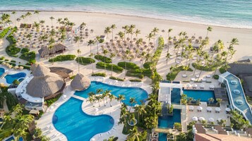 Un resort con varias piscinas, palmeras y acceso a la playa.
