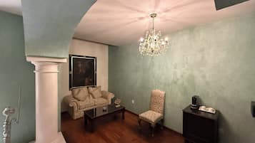Una sala de estar con una araña, un sofá, un sillón y una mesa de centro.
