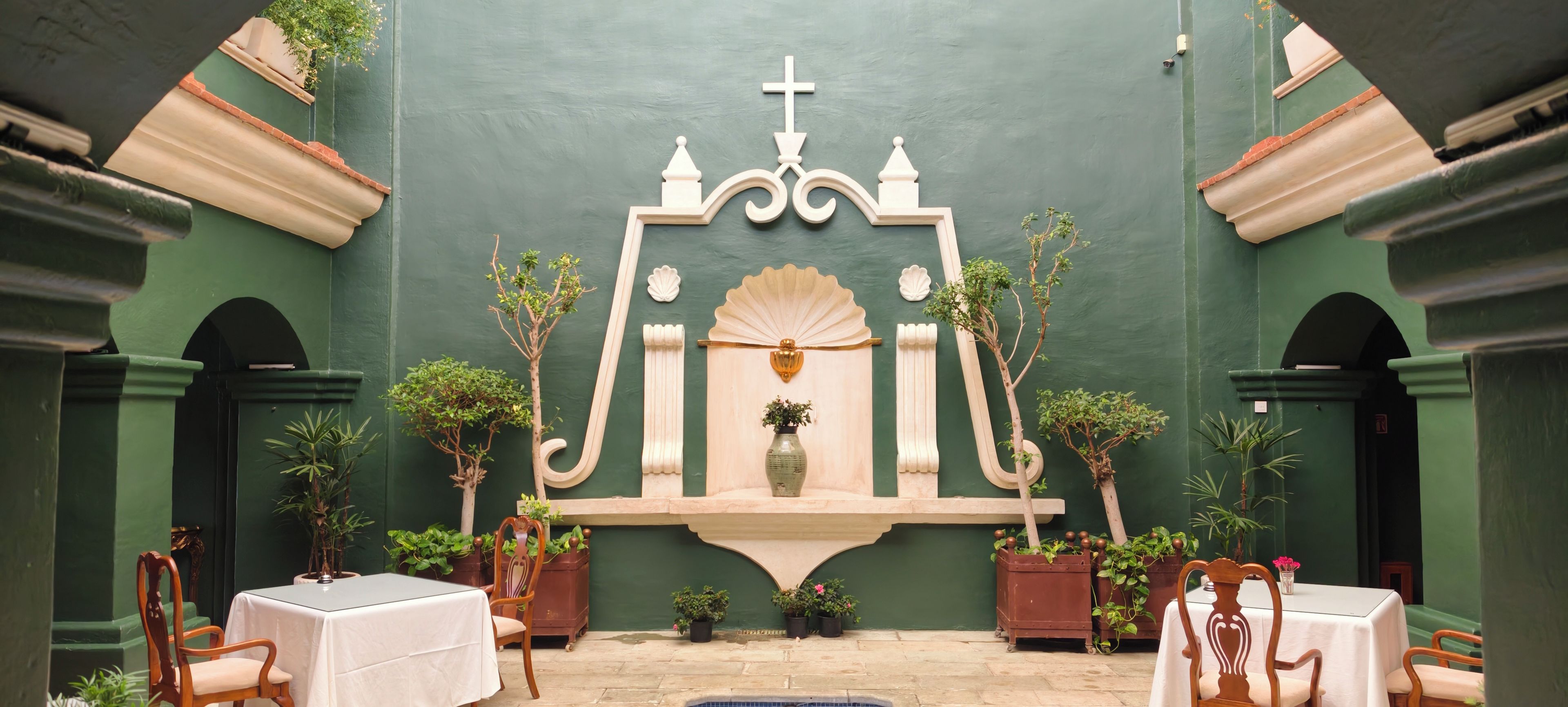A chapel with a central altar, pews, and potted plants.
