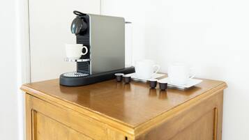 A coffee machine with a cup and saucer, and two small cups on a wooden counter.